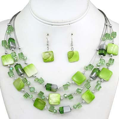 A green beaded jewelry set displayed on a white mannequin bust, including a multi-strand necklace and matching drop earrings with light and dark green square and cylindrical beads.