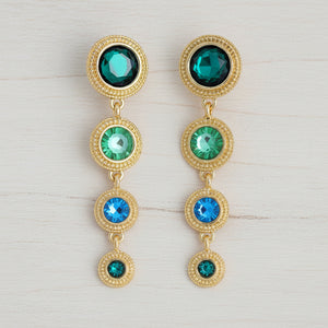 Gold earrings with green and blue gemstones on a white background