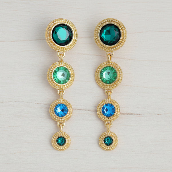 Gold earrings with green and blue gemstones on a white background