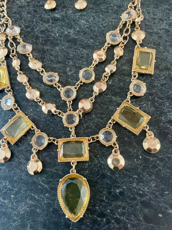Delicate gold necklace with green gemstones on a dark surface