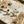 Load image into Gallery viewer, Gold infinity-shaped earrings on a marble surface with seashells and sand.
