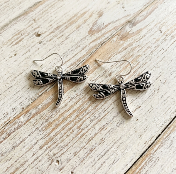 Silver dragonfly earrings on a wooden surface