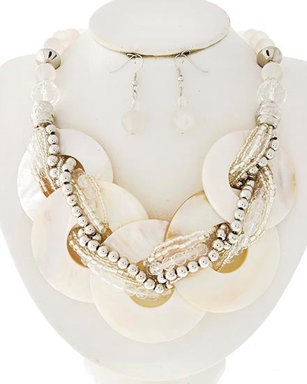 A statement necklace and matching drop earrings displayed on a white mannequin bust. The necklace features large circular shell-like discs, clear faceted beads, and silver-tone beaded strands.