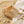 Load image into Gallery viewer, Stack of gold bangles with diamond accents on a sandy surface with stones.
