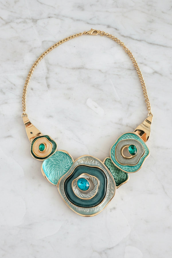 Decorative necklace with circular design and turquoise stones on a dark surface