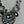 Load image into Gallery viewer, A close-up of a statement necklace featuring silver-toned filigree rings and oval links set with clear faceted crystals on a light gray textured background.
