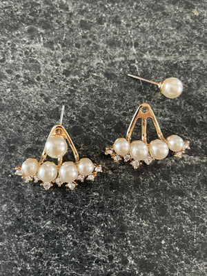 Pearl earrings on a dark textured surface