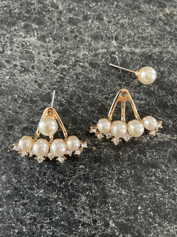 Pearl earrings on a dark textured surface