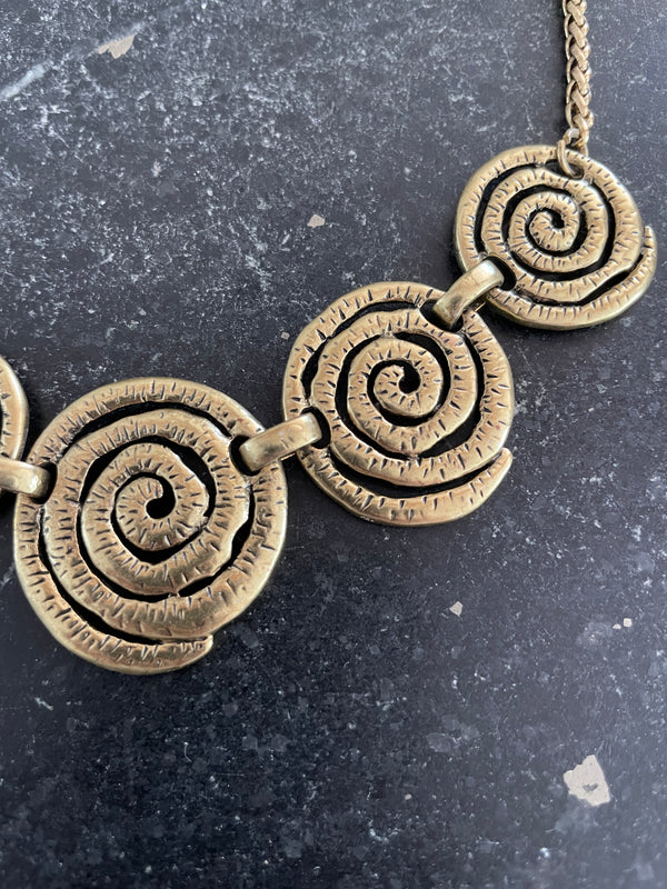 Bronze spiral necklace on a dark textured background