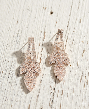 Rose gold earrings on a light wooden surface