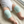 Load image into Gallery viewer, Baby wearing light blue knitted leg warmers on a soft surface

