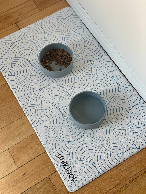 Gray bowls on a patterned mat with 'unikook' branding on a wooden floor.