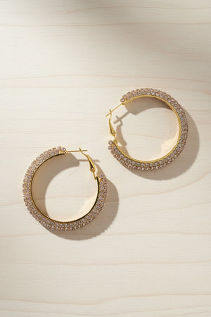 Gold hoop earrings with gemstone accents on a light wooden surface