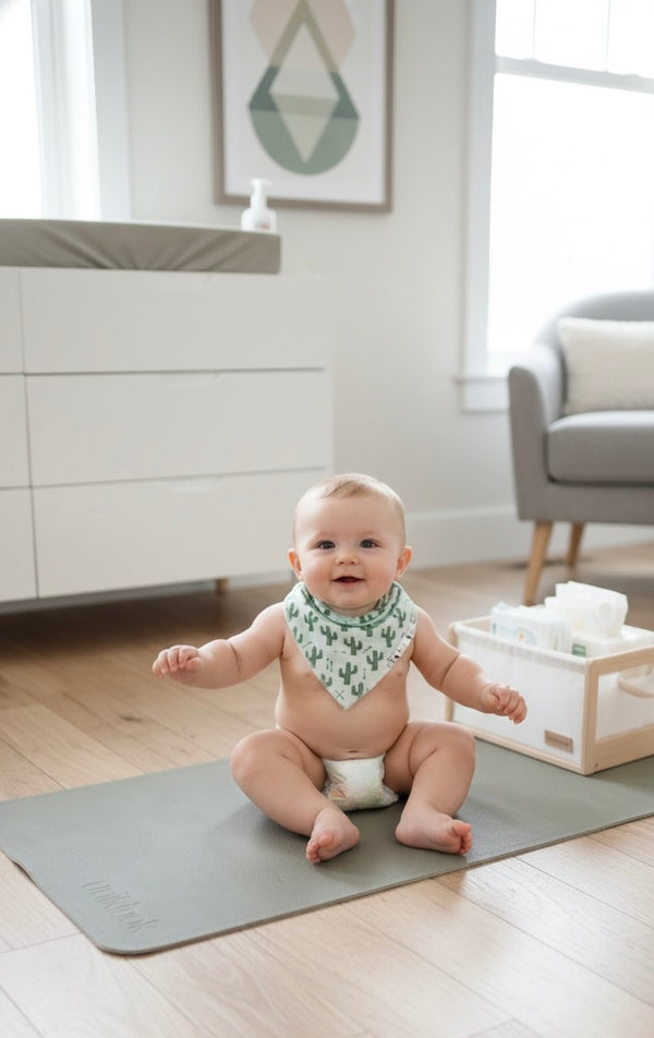 Baby sitting on a mat in a room with a white wall and furniture.