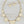 Load image into Gallery viewer, A gold-tone statement necklace and matching drop earrings with shield-shaped cream enamel pendants, displayed on a dark gray stone surface.
