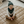 Load image into Gallery viewer, Baby sitting on a round beige mat in a living room with light gray sofas and a lamp.
