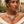 Load image into Gallery viewer, A woman wearing a bohemian-style statement necklace with faux pearls, heart charms, and leaf pendants over a cream off-the-shoulder top.
