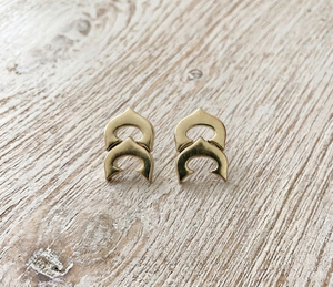 Pair of gold earrings on a light wooden surface