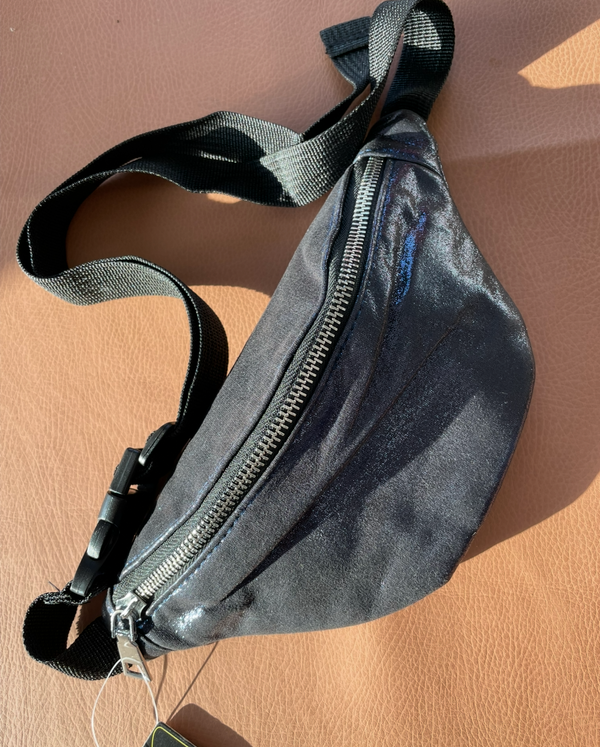 Black waist bag on a beige surface with a visible brand tag.
