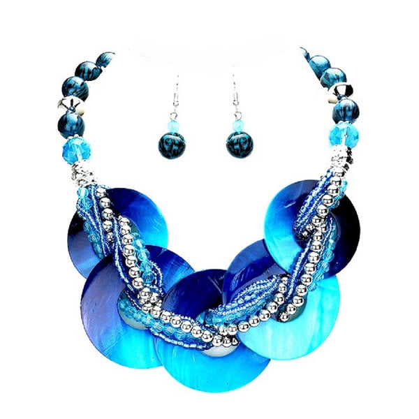 A blue and turquoise statement necklace with matching drop earrings, featuring large iridescent shell-like discs, braided beads, and silver-toned accents on a plain white background.