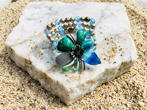 Butterfly-shaped brooch with blue and silver details on a textured stone surface
