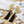 Load image into Gallery viewer, Gold floral earrings with black tassels on a marble surface with stones and shells.
