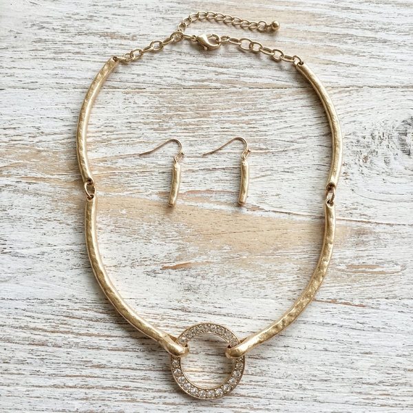 Gold necklace and earrings set on a wooden surface