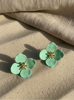 Green floral earrings on a beige fabric background
