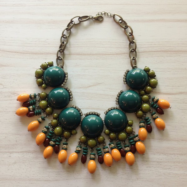 Colorful beaded necklace with green, orange, and red beads on a white background