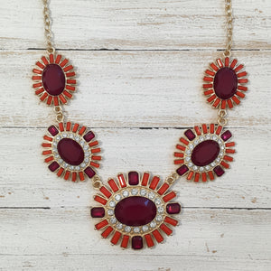 Ornate earrings with red and gold design on a white background