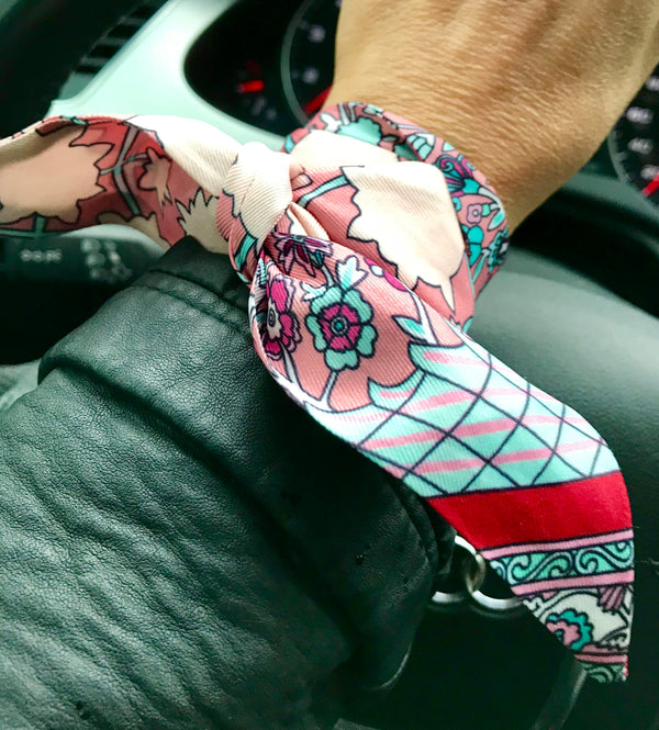 Colorful patterned handbag strap draped over a car seat.