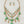 Load image into Gallery viewer, Necklace with green gemstones and gold chain on a dark surface
