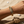 Load image into Gallery viewer, Gold feather bracelet on a wrist with a sandy background
