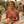 Load image into Gallery viewer, Woman holding a bouquet of flowers in an outdoor setting with stone architecture and plants.
