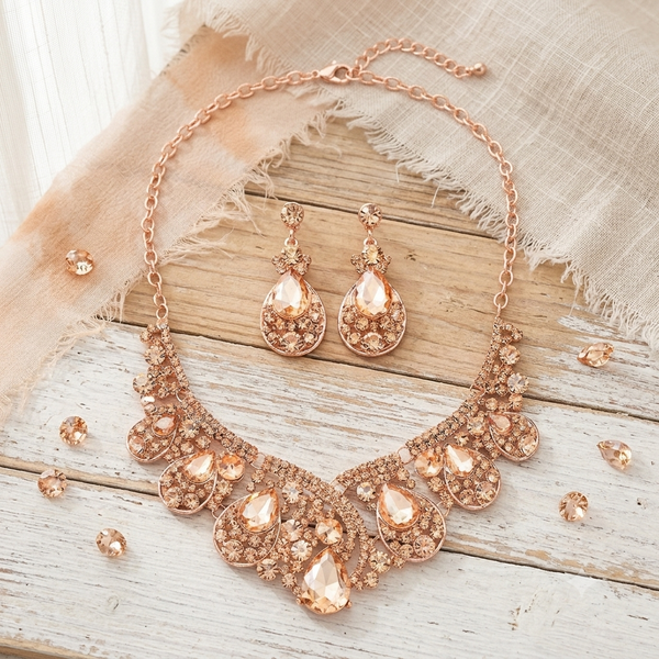Rose gold jewelry set with necklace and earrings on a wooden surface