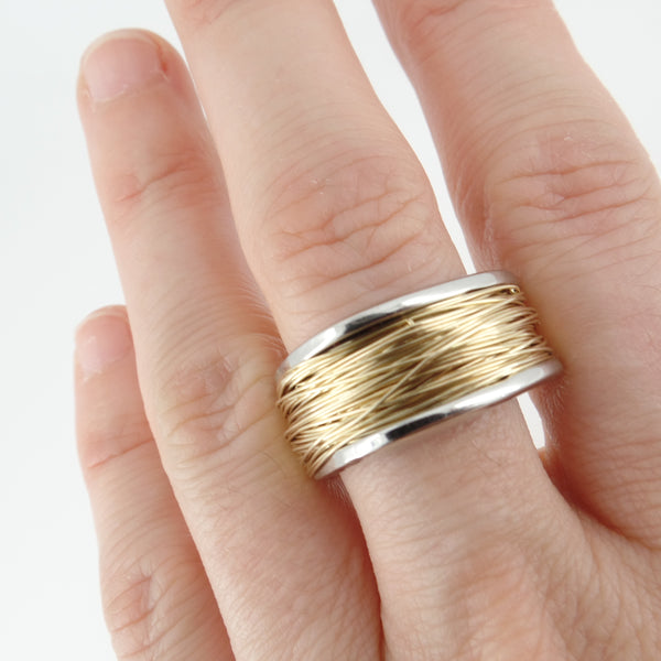 Gold and silver ring on a finger against a white background