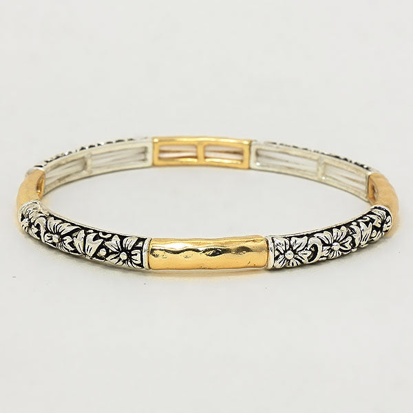 Gold and silver bracelet with floral patterns on a light gray background