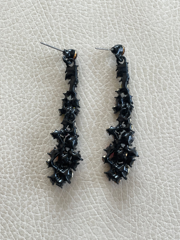 Pair of black earrings on a light gray textured surface
