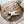 Load image into Gallery viewer, A baby lying on a round quilted floor mat in tan and gray colors with plush toys attached to it.
