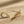 Load image into Gallery viewer, Gold wing-shaped bracelet on a sandy surface
