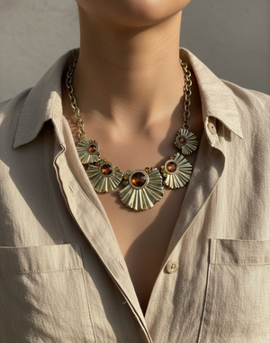 Necklace with sunflower design worn by a person in a beige shirt.