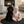 Load image into Gallery viewer, Child in a pink outfit with a heart-themed bib sitting next to a black dog on a black mat in a living room.

