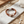 Load image into Gallery viewer, Brown leather bracelet with pearls on a marble surface with sand and shells.
