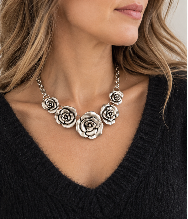 Burnished silver rose necklace worn with a black knit top, lifestyle photo