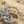 Load image into Gallery viewer, A silver-toned textured bracelet with interlocking circular links and a coin charm, displayed on sandy beach ground.
