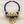 Load image into Gallery viewer, A statement bib-style necklace featuring a thick navy blue braided cord, gold-tone metal accents, white and yellow fabric panels, and dangling clear faceted crystal beads, displayed on a light wood background.
