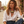 Load image into Gallery viewer, A woman wearing a white button-down shirt and blue jeans sits outdoors, wearing a chunky statement necklace with yellow, blue, and white beads and silver-toned charms.
