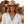 Load image into Gallery viewer, A smiling woman wearing a tan cowboy hat, white button-up shirt, and layered silver necklaces with a large turquoise pendant, photographed outdoors against a blurred rustic wooden building.
