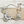 Load image into Gallery viewer, An ornate bib-style statement necklace with silver-toned teardrop rhinestones and gold-toned chain links, displayed on a light wood plank background.

