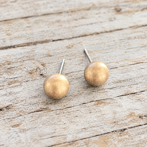 Matte gold ball stud earrings on pale rustic wood